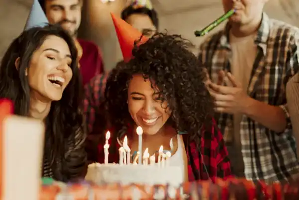 women blowing out candles of her birthday cake