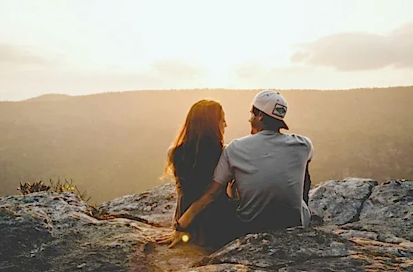 couple sitting down cuddling up over a rock edge